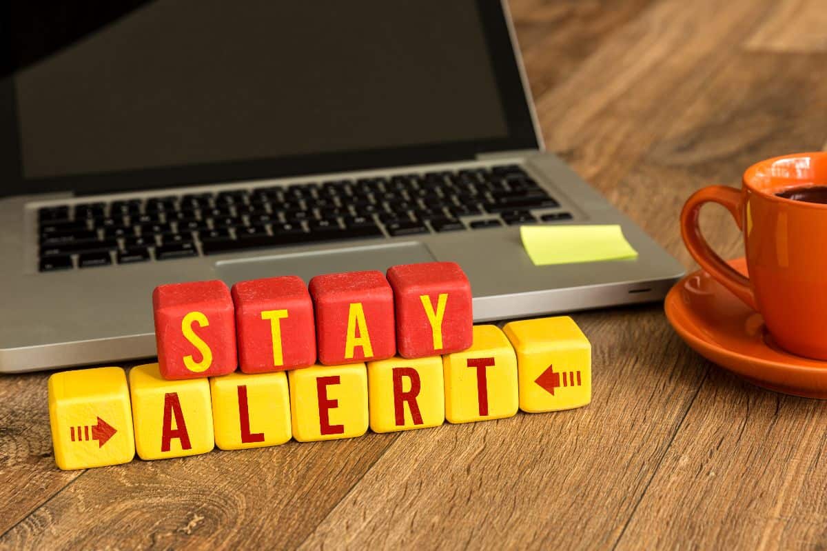 Stay alert spelled out in scrabble in front of a laptop.