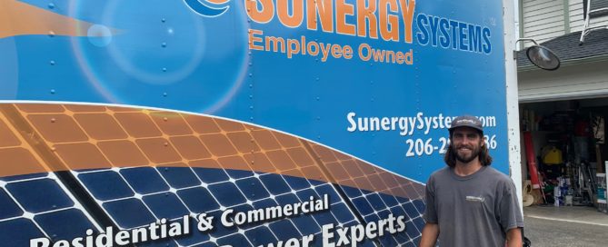 Sunergy Systems work truck with an installer standing in front of it.